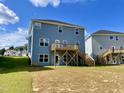 Back exterior featuring a wooden deck with stairs leading to a spacious backyard at 303 Bishop Ln, Sanford, NC 27330