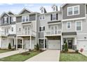 Well-manicured townhomes with charming exteriors, driveways, and a green lawn under a sunny sky at 125 Sugar Run Dr # 26, Fuquay Varina, NC 27526