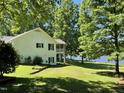 Backyard view of a white brick home featuring a screened porch and waterfront access at 3309 Westcott Cir, Sanford, NC 27330