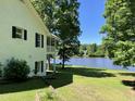 Spacious backyard featuring a view of a lake, mature trees, a screened porch, and black framed windows at 3309 Westcott Cir, Sanford, NC 27330