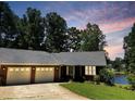 Inviting brick home showcases a two-car garage and serene lake views, framed by mature trees at 3309 Westcott Cir, Sanford, NC 27330