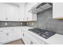 Modern kitchen featuring white cabinets, stainless steel range hood, sleek countertops, and stylish backsplash at 1505 Patchings Ln, Knightdale, NC 27545