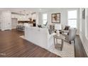 Bright, open-concept living room with wood floors, a modern sofa, and an adjacent eat-in kitchen at 1505 Patchings Ln, Knightdale, NC 27545