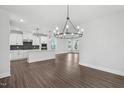 Open concept living room and kitchen boasts modern lighting, wood flooring, and neutral paint at 1505 Patchings Ln, Knightdale, NC 27545