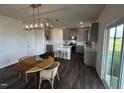 Open-concept kitchen features an island, stainless steel appliances, and an adjacent dining area with modern light fixture at 191 Robert Howe Dr, Fuquay Varina, NC 27526