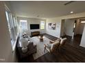 Bright living room with hardwood floors, large windows, a comfortable sofa, stylish chairs, and modern decor at 191 Robert Howe Dr, Fuquay Varina, NC 27526