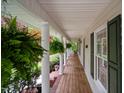 Relaxing side porch with white columns, ferns, and verdant landscaping at 2723 New Sharon Church Rd, Hillsborough, NC 27278