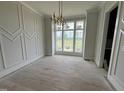 Bright dining area featuring decorative trim, modern chandelier, and large windows offering scenic views at 4905 Hidden Pasture Way, Zebulon, NC 27597