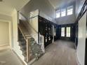 Spacious entryway with stairs, modern black railing, wood floors, and natural light from the front door at 4905 Hidden Pasture Way, Zebulon, NC 27597
