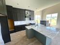 Contemporary kitchen boasts dark cabinetry, an island with a marble countertop, and stainless steel appliances at 4905 Hidden Pasture Way, Zebulon, NC 27597