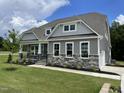 Beautiful home with gray siding, stone accents, covered porch, landscaped yard, and an attached garage at 55 Browning Mill Dr, Wendell, NC 27591