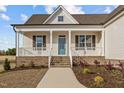 Charming single-story home featuring a welcoming front porch, manicured landscaping, and a stylish blue front door at 65 Diamond Creek Dr, Zebulon, NC 27597