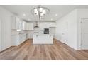 Bright, open kitchen with white cabinetry, island, modern lighting, and stainless appliances at 305 Chestnut Oak Ln, Lillington, NC 27546