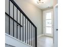 Bright foyer with light hardwood floors, a modern light fixture, and a staircase with a black iron railing at 1156 Cottonsprings Dr, Wendell, NC 27591