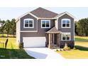 Charming two-story home with gray siding, a white garage door, and a well-manicured front lawn at 592 Barbour Farm Ln, Four Oaks, NC 27524