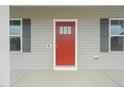 Close-up of a vibrant red front door with sidelight windows and contrasting gray shutters at 148 Harmony Trl, Broadway, NC 27505