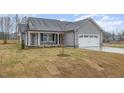 Inviting single-story home with gray siding, stone accents, and a two-car garage, surrounded by a fresh lawn at 106 Burnello Ct, Princeton, NC 27569