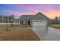 Beautiful single-story home with gray siding and stone accents, a two-car garage, and a well-manicured front yard at dusk at 106 Burnello Ct, Princeton, NC 27569