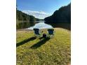 Scenic lake view with chairs on the grassy shore offering a peaceful retreat surrounded by nature and clear skies at 1820 Oatlands Court Ct, Wake Forest, NC 27587