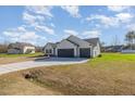 Back exterior view showcasing a three-car garage, set against a backdrop of a blue, cloudy sky at 102 Burnello Ct, Princeton, NC 27569