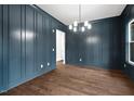 Formal dining room with dark blue wall paneling, hardwood floors, and chandelier at 406 Terry Rd, Hillsborough, NC 27278