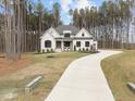 An elegant cream-colored house features a long, curved driveway and meticulously maintained landscaping in a wooded location at 7440 Summer Tanager Trl, Raleigh, NC 27614