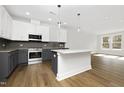 Bright kitchen featuring a granite island, stainless appliances, gray cabinets, and hardwood floors at 320 Church St, Morrisville, NC 27560