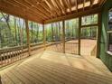 An expansive screened in porch area with wood floors and rails offers views of the surrounding lush greenery at 111 Gaines Trail, Pittsboro, NC 27312