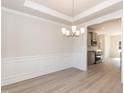 Elegant dining room with modern chandelier, wood floors, and access to the kitchen at 136 Newport Lndg, Garner, NC 27529