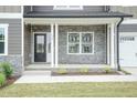 Inviting entryway featuring stone accents, a black front door, and a well-maintained lawn showcasing the home's charm at 136 Newport Lndg, Garner, NC 27529