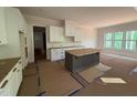 Well-lit kitchen featuring white cabinetry, a dark central island, and large windows at 162 Gaines Trail, Pittsboro, NC 27312