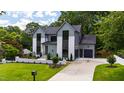Exterior shot showcasing a modern home with a well-manicured lawn, and long driveway at 5208 Knollwood Rd, Raleigh, NC 27609