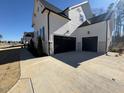 Two-car garage with black doors and light-colored concrete driveway at 183 Inspiration Way, Fuquay Varina, NC 27526
