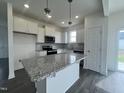 Bright kitchen featuring stainless appliances, ample counter space, hardwood floor, and a central kitchen island at 189 Waterwheel Dr, Selma, NC 27576
