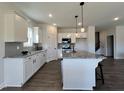 The open kitchen features white cabinets, granite countertops, gray backsplash, and an island with stool seating at 370 E Clydes Point Way, Wendell, NC 27591