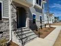 Elegant stone entryway with a covered porch, black iron railing, and newly planted landscaping at 168 Grand Griffon Way, Lillington, NC 27546