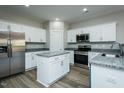 Modern kitchen features stainless steel appliances, granite countertops, an island, and sleek white cabinetry at 146 Tupelo Dr, Spring Hope, NC 27882