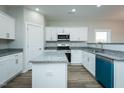 Bright kitchen boasts stainless steel appliances, granite counters, an island, and ample white cabinet storage at 146 Tupelo Dr, Spring Hope, NC 27882