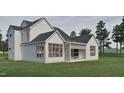 A modern farmhouse-style home with white siding, black roof, outdoor fireplace, and spacious covered patio at 725 Catawba St, Raleigh, NC 27609