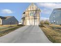 View of a two-story house with gray siding and a long concrete driveway leading to the attached garage at 573 Highview Drive Dr, Benson, NC 27504