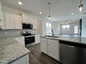Well-equipped kitchen with granite counters, stainless steel appliances, and view into adjacent living room at 234 Danube Dr, Zebulon, NC 27597