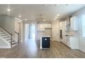 Open-concept living room with wood floors flows into the modern kitchen with an island and stainless appliances at 428 Fast Pitch Ln, Four Oaks, NC 27524