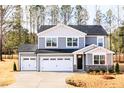 Charming two-story home with gray siding, black roof, and a three-car garage on a concrete driveway at 7404 Prato Ct, Wendell, NC 27591