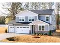A two-story gray home featuring a three-car garage, stone accents, and a manicured lawn at 7404 Prato Ct, Wendell, NC 27591