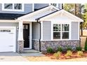 Close-up of the home's entrance featuring a black door, stone accents, and manicured landscaping at 7404 Prato Ct, Wendell, NC 27591