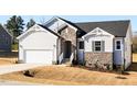 New home features stone facade, light siding, a two-car garage, and a concrete driveway at 472 Barbour Farm Ln, Four Oaks, NC 27524