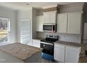 Modern kitchen with white cabinets, stainless steel appliances, and an island at 5004 Macleod Pl, Zebulon, NC 27597