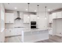 Bright, modern kitchen with stainless steel appliances, a large island, and stylish pendant lighting at 370 Fast Pitch Ln, Four Oaks, NC 27524