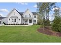 Beautiful white two-story home with a black door, green lawn, and professional landscaping at 2506 Silas Peak Ln, Apex, NC 27523