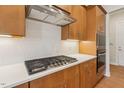 This kitchen features modern appliances, custom cabinetry, quartz counters, and white tile backsplash at 208 Regency Ridge Dr, Holly Springs, NC 27540